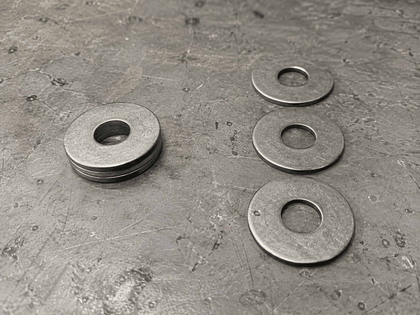 AI illustration of stacked washers beside three separated washers on a worn workshop bench.